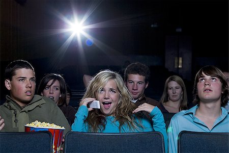 Girl talking on cell phone at movie theater with annoyed boy Stock Photo - Premium Royalty-Free, Code: 640-02773408