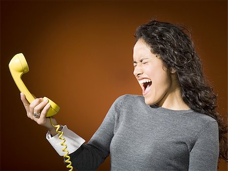 Woman holding retro phone and yelling Stock Photo - Premium Royalty-Free, Code: 640-02773444