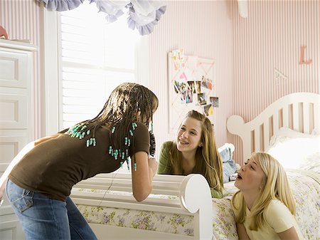 Girl singing into hairbrush in bedroom with girlfriends laughing Stock Photo - Premium Royalty-Free, Code: 640-02773538