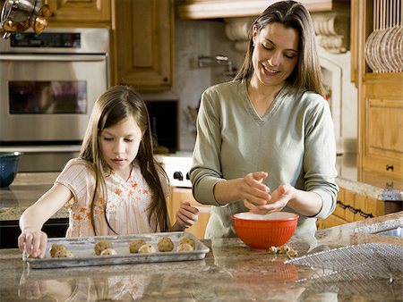 Girl in kitchen with woman baking cookies Stock Photo - Premium Royalty-Free, Code: 640-02773560