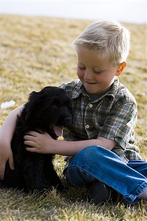 simsearch:640-06050836,k - Boy sitting on grass outdoors with puppy Stock Photo - Premium Royalty-Free, Code: 640-02773579
