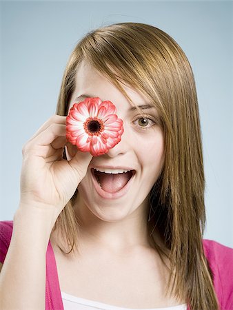 simsearch:640-02770772,k - Close-up of woman smiling holding flower up to her eye Stock Photo - Premium Royalty-Free, Code: 640-02773809