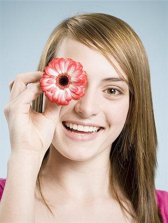 simsearch:640-02773811,k - Close-up of woman smiling holding flower up to her eye Stock Photo - Premium Royalty-Free, Code: 640-02773810