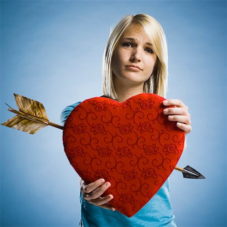 woman holding up a heart with an arrow through it Stock Photo - Premium Royalty-Free, Code: 640-02947887