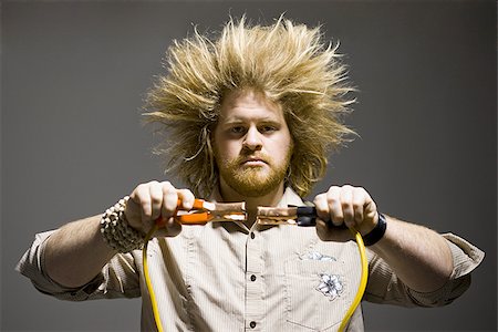 electrocuted - man with crazy hair holding jumper cables Stock Photo - Premium Royalty-Free, Code: 640-02949251