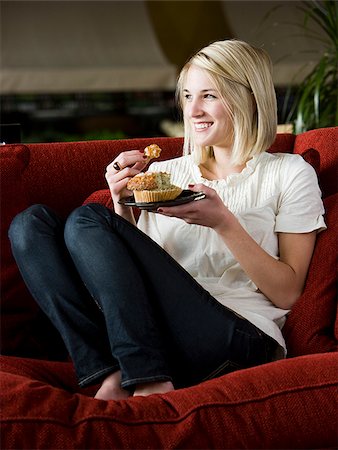 simsearch:640-02948353,k - woman eating a muffin on a red sofa Foto de stock - Royalty Free Premium, Número: 640-02949579