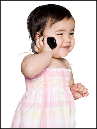 baby girl in a pink dress holding a cell phone Stock Photo - Premium Royalty-Free, Code: 640-02949617