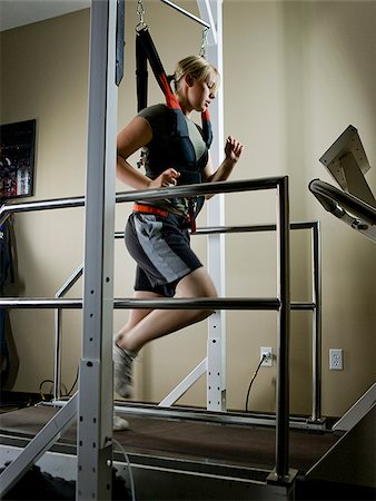 suspended - young woman running on a treadmill in a harness Stock Photo - Premium Royalty-Free, Code: 640-02949651