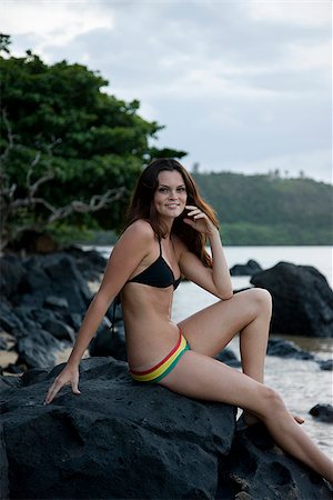 woman in a bikini sitting on the rocks at the beach Stock Photo - Premium Royalty-Free, Code: 640-02949900