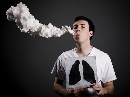 man with a lit cigarette holding up a drawing of black lungs in front of his chest Stock Photo - Premium Royalty-Free, Code: 640-02949996
