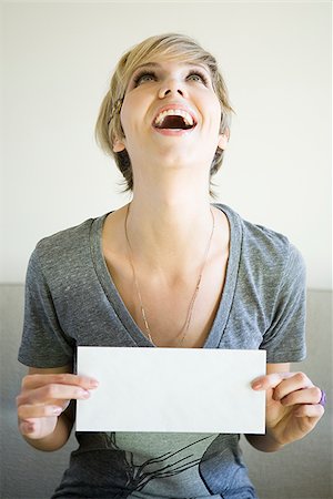 enveloppe - woman sitting on a couch holding up an envelope Foto de stock - Sin royalties Premium, Código: 640-02950159