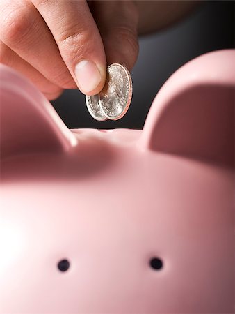 piggy bank hand - hand putting two quarters in a piggy bank Stock Photo - Premium Royalty-Free, Code: 640-02950609