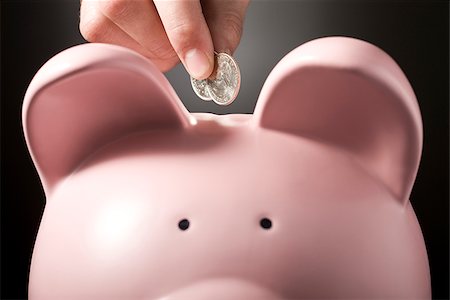 piggy bank hand - hand putting two quarters in a piggy bank Stock Photo - Premium Royalty-Free, Code: 640-02950610