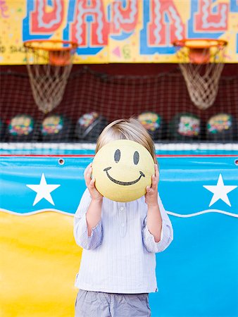 little boy holding up a smiley face at a carnival Foto de stock - Sin royalties Premium, Código: 640-02951504