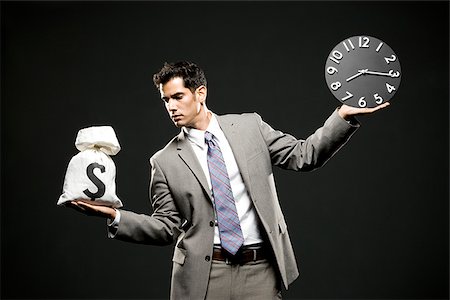 businessman holding a clock and a bag of money Stock Photo - Premium Royalty-Free, Code: 640-02952269