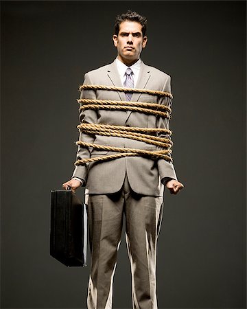 businessman in a full suit tied up with a rope around his mid section Foto de stock - Sin royalties Premium, Código: 640-02952260