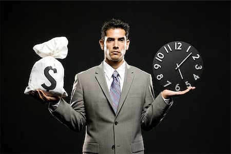 businessman holding a clock and a bag of money Stock Photo - Premium Royalty-Free, Code: 640-02952272