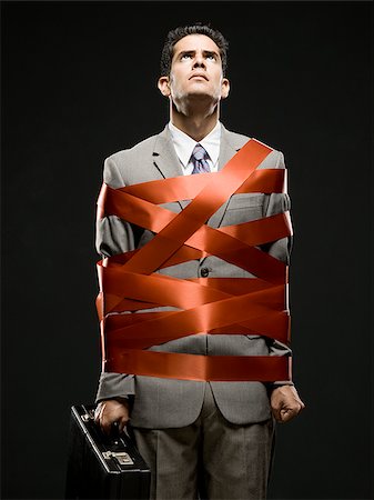 businessman wrapped up with red tape Stock Photo - Premium Royalty-Free, Code: 640-02952288