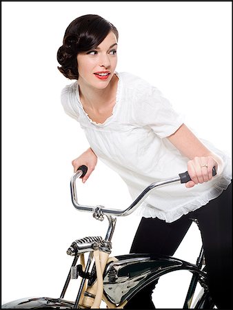 woman with her hair up in a classic hollywood hairstyle reminiscent of the 1940s riding a bike Stock Photo - Premium Royalty-Free, Code: 640-02952466