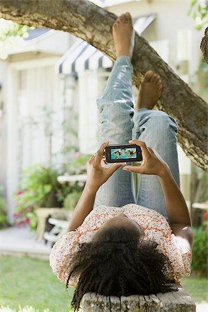 woman lying under a tree watching a portable media device Stock Photo - Premium Royalty-Free, Code: 640-02952639