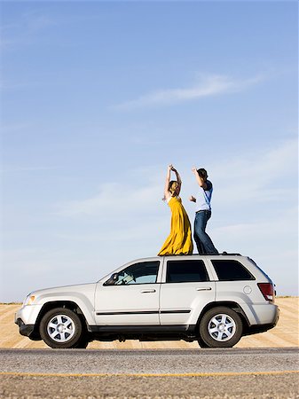 sport utility vehicle - couple on the roof of their car on the side of the road Stock Photo - Premium Royalty-Free, Code: 640-02952783