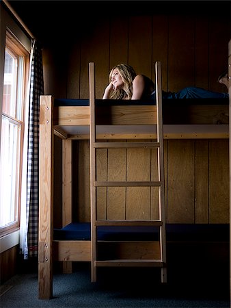 woman lying on the top bunk of a bunk bed Fotografie stock - Premium Royalty-Free, Codice: 640-02953003