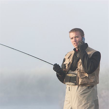 portraits of fishermen - man fishing in a river on his cell phone Stock Photo - Premium Royalty-Free, Code: 640-02953126