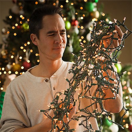 man untangling christmas tree lights Stock Photo - Premium Royalty-Free, Code: 640-02953175