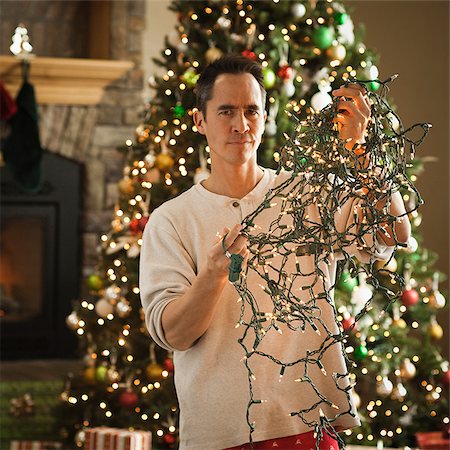 man untangling christmas tree lights Stock Photo - Premium Royalty-Free, Code: 640-02953173