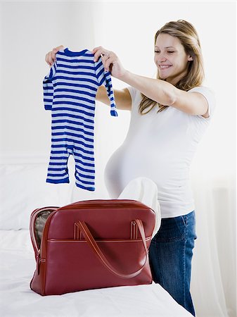 pregnant woman holding up baby clothing Stock Photo - Premium Royalty-Free, Code: 640-02953252