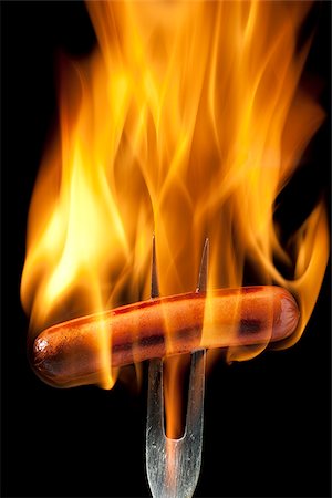 hot dog on a fork completely engulfed in flames Foto de stock - Sin royalties Premium, Código: 640-02953467