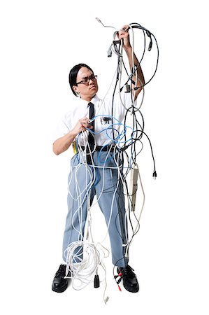 Office worker with tangled mess of wires Stock Photo - Premium Royalty-Free, Code: 640-03256179