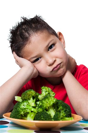 Boy with plate of broccoli frowning Stock Photo - Premium Royalty-Free, Code: 640-03256223