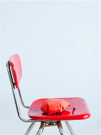 Red whoopie cushion on red spotted chair, studio shot Stock Photo - Premium Royalty-Free, Code: 640-03256535