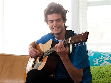 playing guitar on sofa - USA, Utah, Provo, young man playing guitar in living room Stock Photo - Premium Royalty-Free, Code: 640-03256601