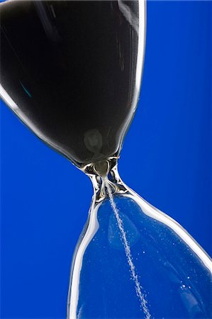 Close-up of hourglass on blue background Stock Photo - Premium Royalty-Free, Code: 640-03256627