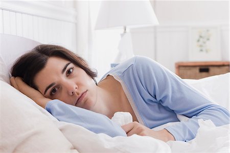 sad adult looking at camera - USA, Utah, Orem, portrait of young woman lying in bed Stock Photo - Premium Royalty-Free, Code: 640-03256702