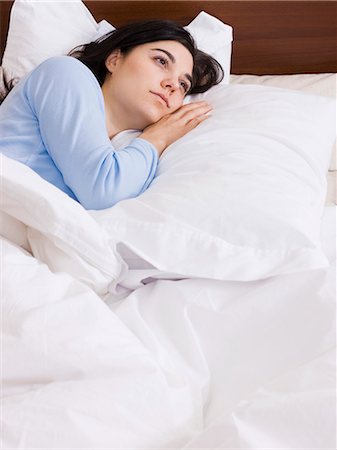 Woman lying down in bed stock photo