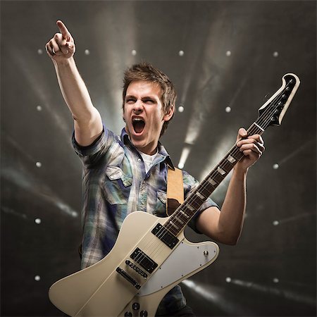 rock and roll - Young man playing bass guitar, studio shot Foto de stock - Sin royalties Premium, Código: 640-03256802