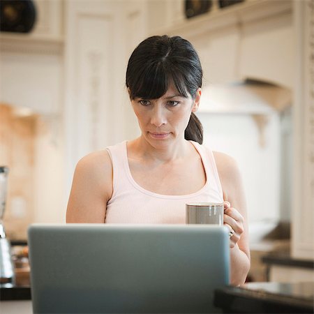 simsearch:640-03256844,k - USA, Utah, Alpine, mid adult woman standing near laptop and holding mug Stock Photo - Premium Royalty-Free, Code: 640-03256833