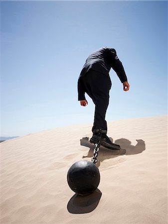 USA, Utah, Little Sahara, mid adult businessman pulling ball in chain on desert, rear view, low angle view Stock Photo - Premium Royalty-Free, Code: 640-03257052