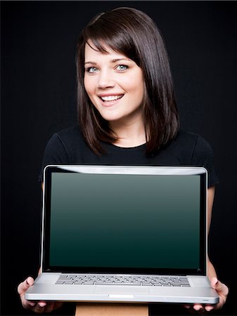 simsearch:640-03257317,k - Young woman showing laptop, studio shot Fotografie stock - Premium Royalty-Free, Codice: 640-03257313