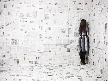 simsearch:640-03256374,k - Rear view of young woman standing in corner of newspapers covered room, studio shot Stock Photo - Premium Royalty-Free, Code: 640-03257328