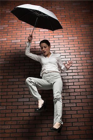 scared young woman one not man not asian - Studio shot of young woman falling holding umbrella Stock Photo - Premium Royalty-Free, Code: 640-03257419