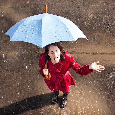 person and raincoat and umbrella - Young woman standing in rain holding umbrella Stock Photo - Premium Royalty-Free, Code: 640-03257680