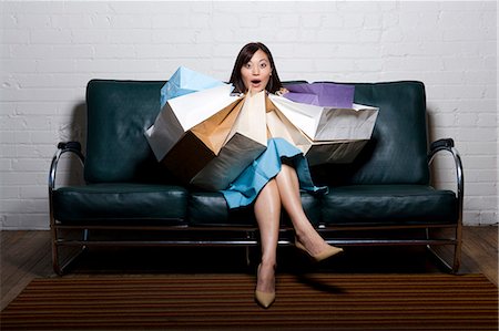 Woman sitting on couch with shopping bags Stock Photo - Premium Royalty-Free, Code: 640-03259409