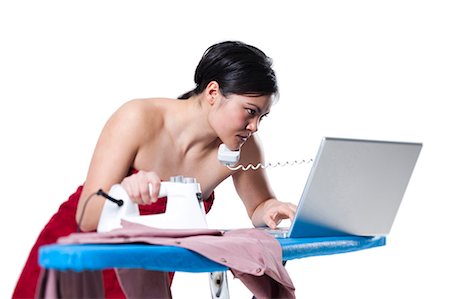 Woman ironing and working on laptop Stock Photo - Premium Royalty-Free, Code: 640-03264690