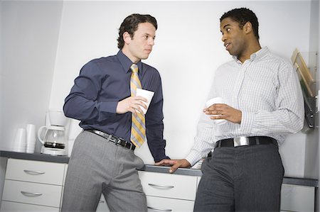 Close-up of two businessmen leaning against a drawer and looking at each other Stock Photo - Premium Royalty-Free, Code: 640-03265486