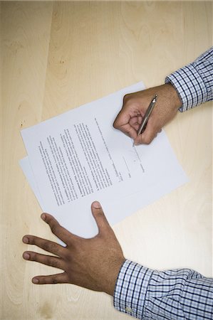 High angle view of a mid adult man's hand signing a document Stock Photo - Premium Royalty-Free, Code: 640-03265489