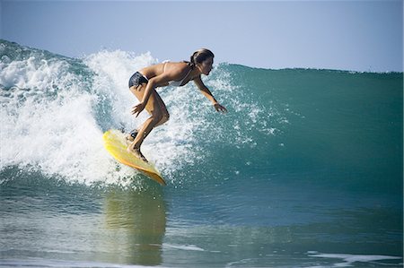 Profile of a young woman surfing on a surfboard Stock Photo - Premium Royalty-Free, Code: 640-03265530